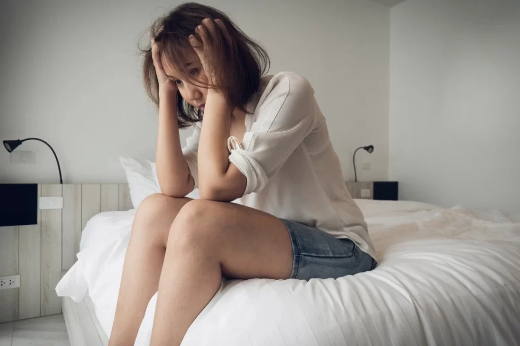 Depressed Woman sitting on the bed with down head 