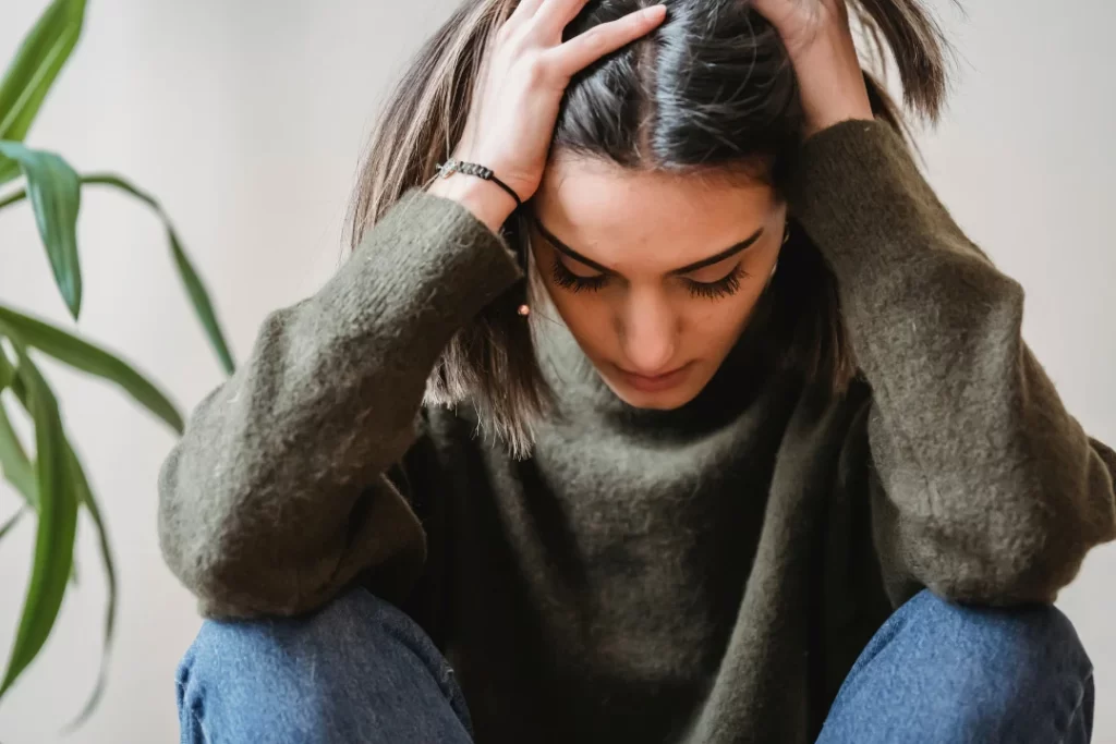 A young lady is suffering from anxiety, sitting with a down head.