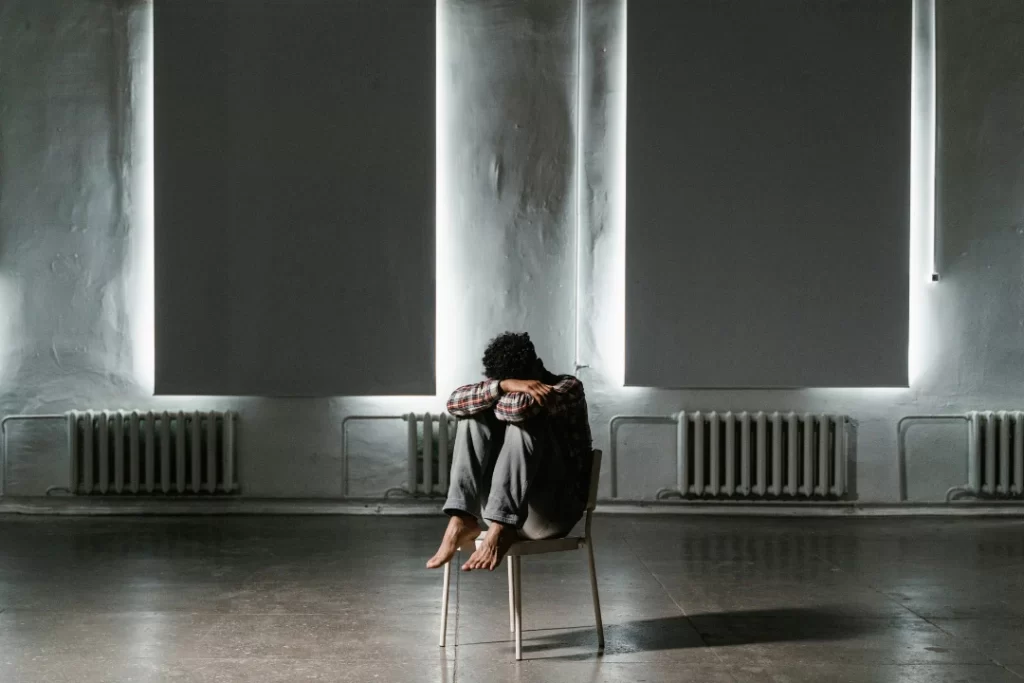 young adult sitting on a chair suffering from depression.