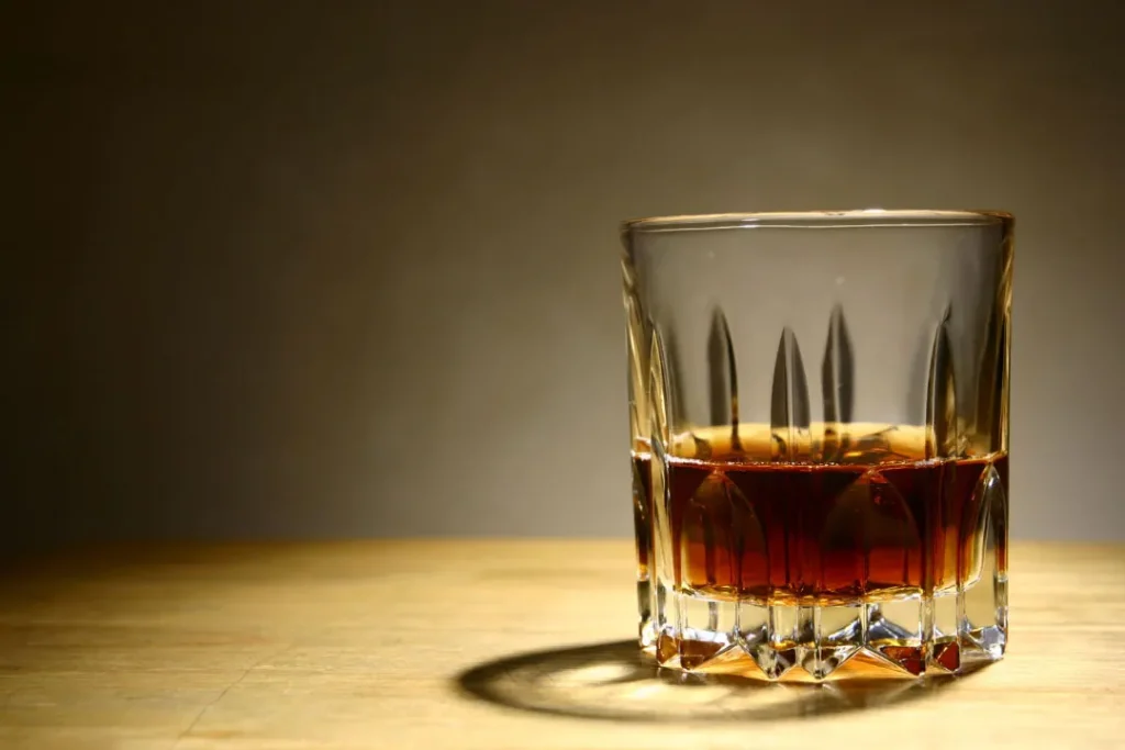 a glass of alcohol on a wooden table