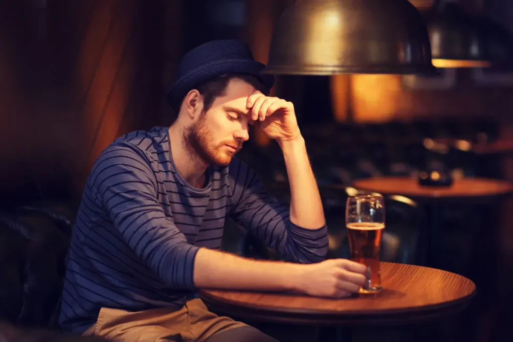A man is sad while having a glass of alcohol. 